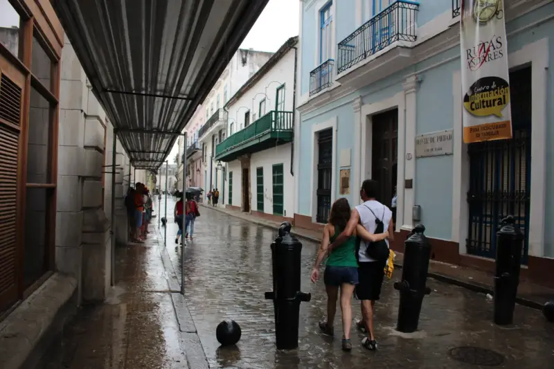 Calle de los Oficios en La Habana Vieja mojada por la lluvia, con edificios coloniales y bolardos negros