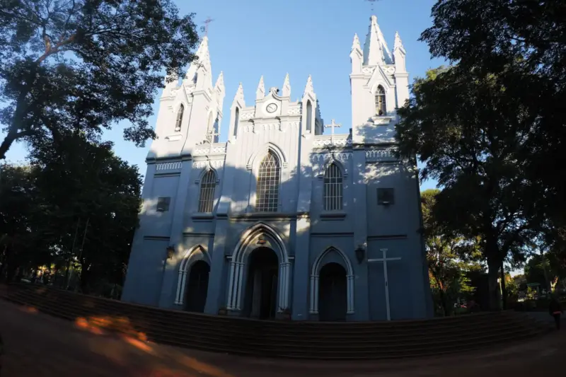 Fachada blanca de estilo neogótico de la catedral de San Lorenzo, en Paraguay, rodeada de árboles
