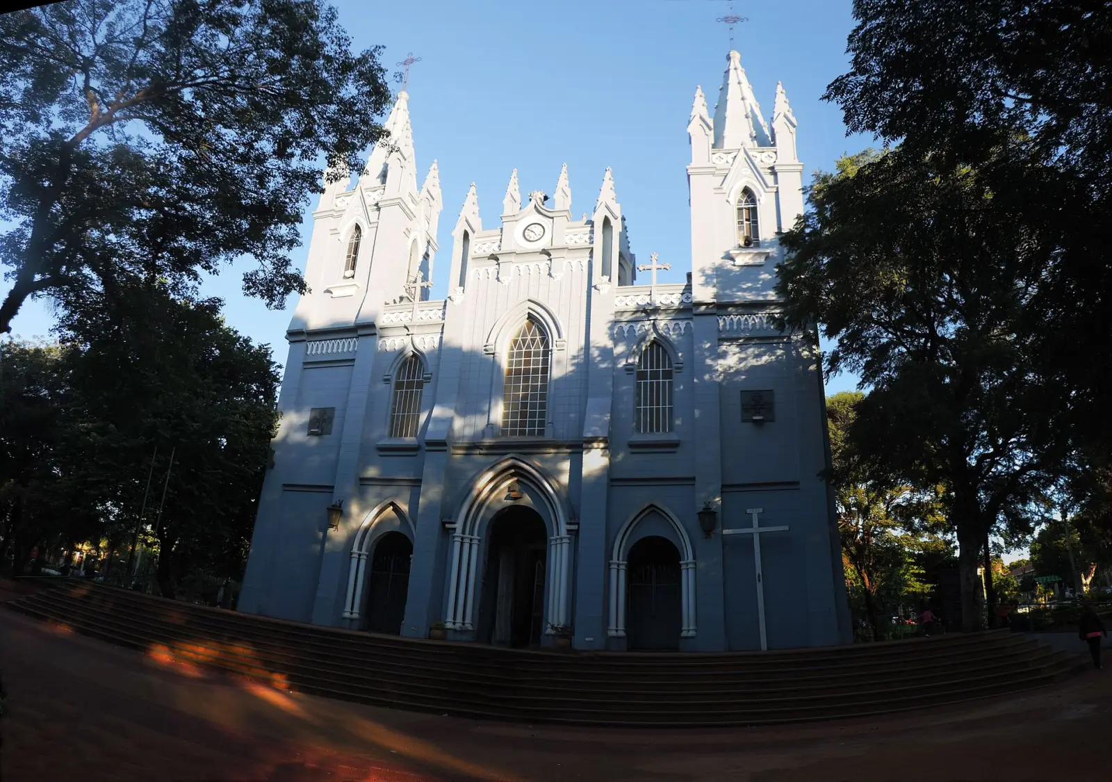 Fachada blanca de estilo neogótico de la catedral de San Lorenzo, en Paraguay, rodeada de árboles