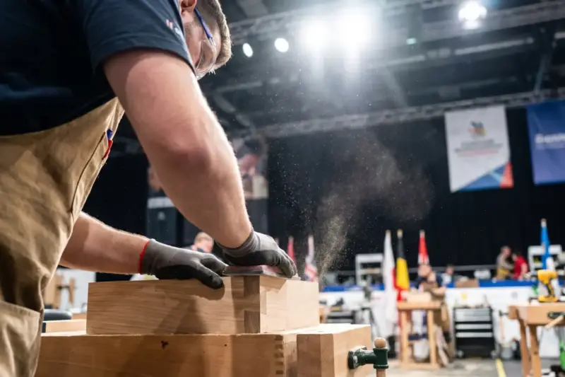 Joven ebanista trabaja una pieza de madera en una competición internacional de formación profesional