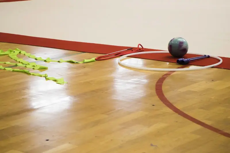 Cinta, aro, pelota y mazas de gimnasia rítmica sobre el suelo de madera de un pabellón