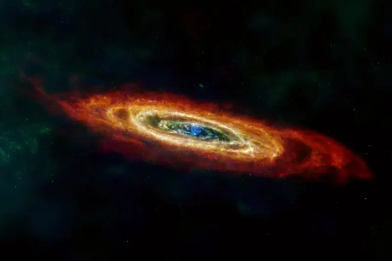 Galaxia de Andrómeda vista en infrarrojo, con anillos de polvo en tonos rojos y naranjas sobre fondo oscuro