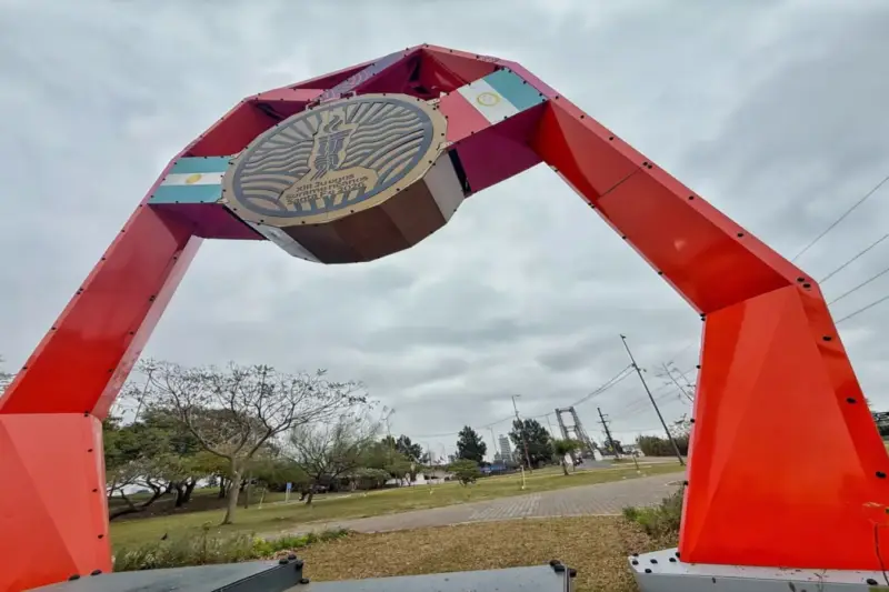 Gran arco rojo con el emblema de los Juegos Suramericanos 2026 y banderas argentinas en un parque de Santa Fe