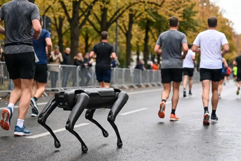 Robot cuadrúpedo corre por una carretera junto a corredores anónimos durante una maratón urbana