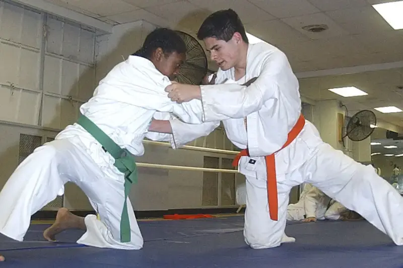 Detalle de una judoca compitiendo sobre un tatami en un campeonato profesional.