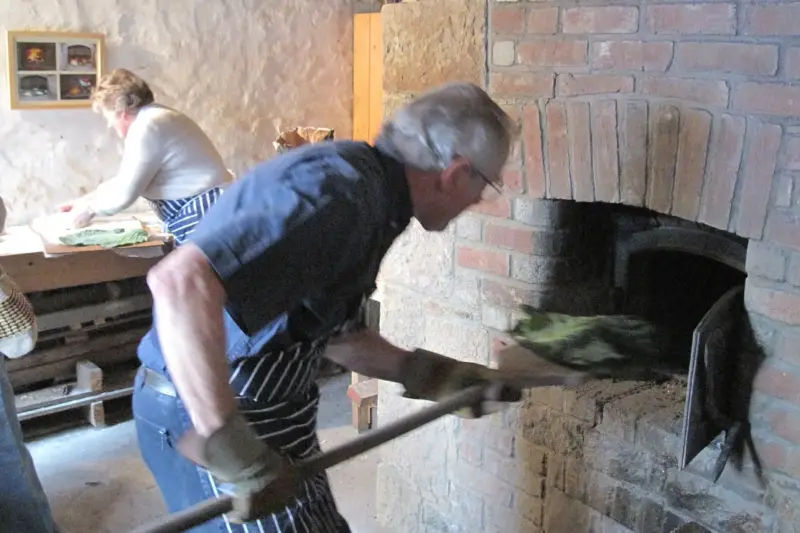 Horno de leña tradicional con brasas en el interior de una panadería rural vacía.