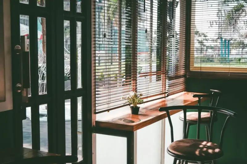 Interior de una cafetería de barrio con mesas de madera, tazas de café y paredes decoradas con murales y fotografías.