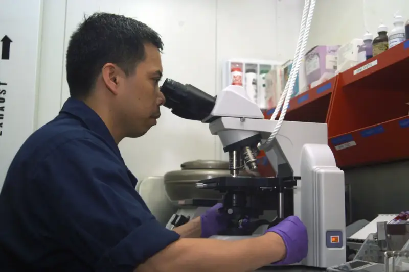 Investigadora con guantes sosteniendo una muestra de sangre en un laboratorio clínico