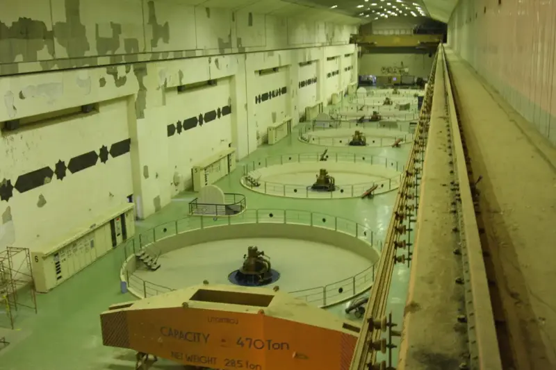 Vista de una gran presa hidroeléctrica con el río y las instalaciones de hormigón bajo la luz de la mañana.