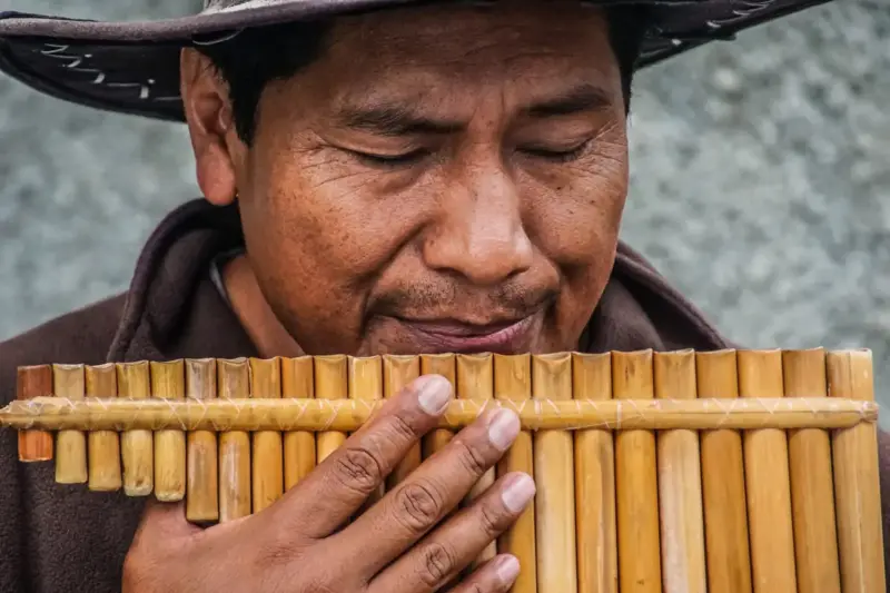 Grupo de músicos con trajes tradicionales andinos reunidos en una plaza de una ciudad boliviana por la mañana.