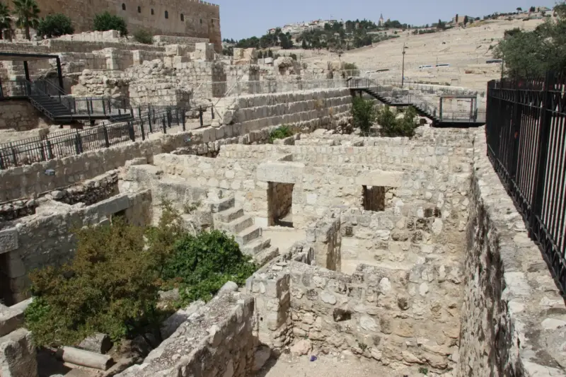 Excavación arqueológica en un abrigo rocoso, con un cordón vegetal retorcido parcialmente expuesto entre el sedimento.