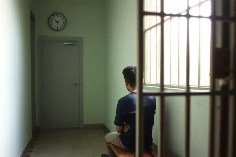 Pasillo sobrio de un centro de justicia juvenil con luz natural entrando por una ventana enrejada