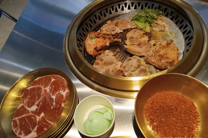 Grupo de personas sentadas en un restaurante de barbacoa con una mesa llena de platos y parrillas