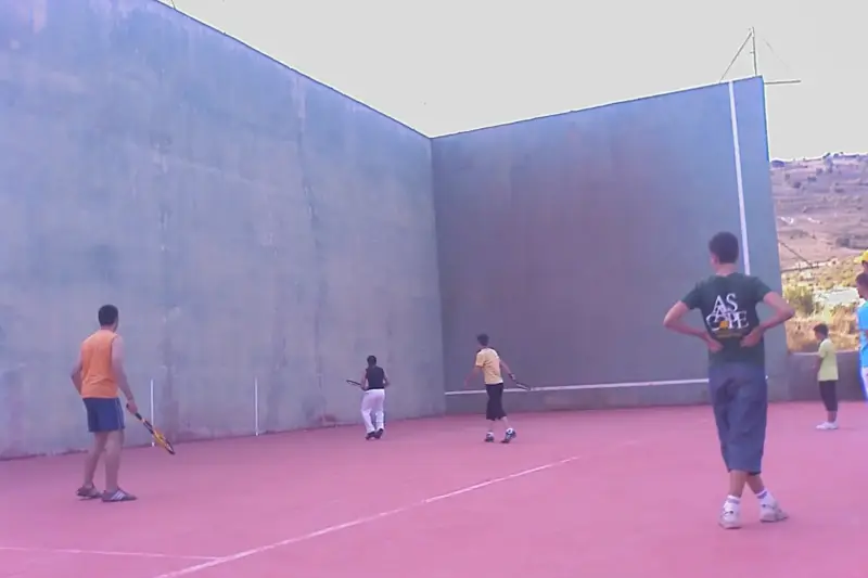Cancha de pelota vasca vacía con una pelota blanca en el suelo y luz de tarde