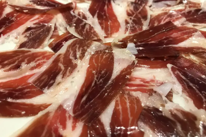 Entrada iluminada de un teatro en un pueblo andaluz, con un jamón ibérico expuesto en primer plano durante una gala.