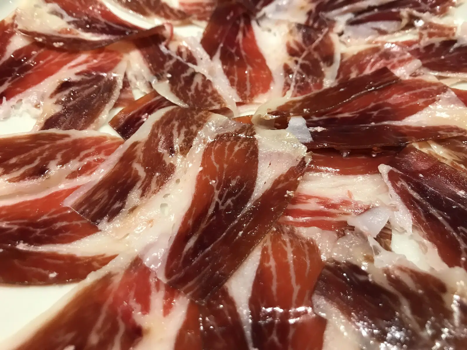 Entrada iluminada de un teatro en un pueblo andaluz, con un jamón ibérico expuesto en primer plano durante una gala.