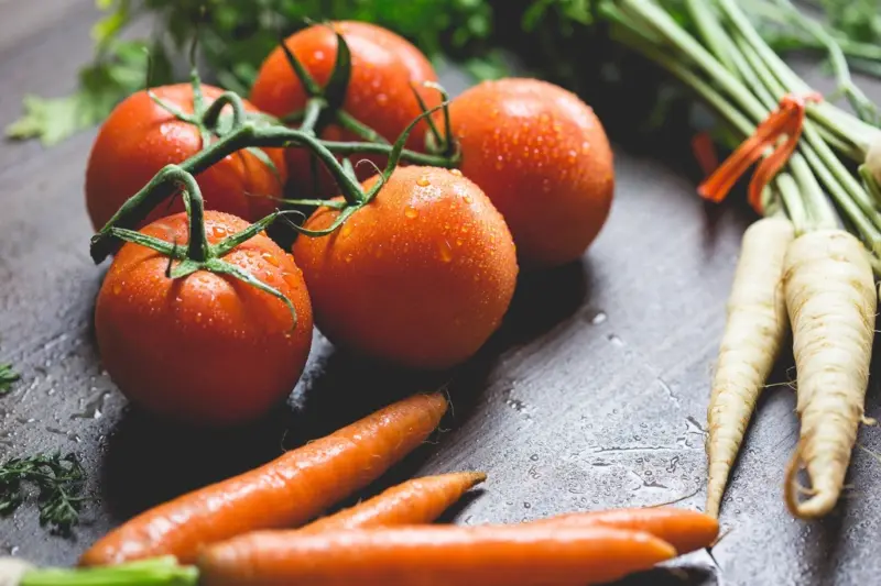 Frutas y verduras frescas sobre una encimera de cocina con luz natural.