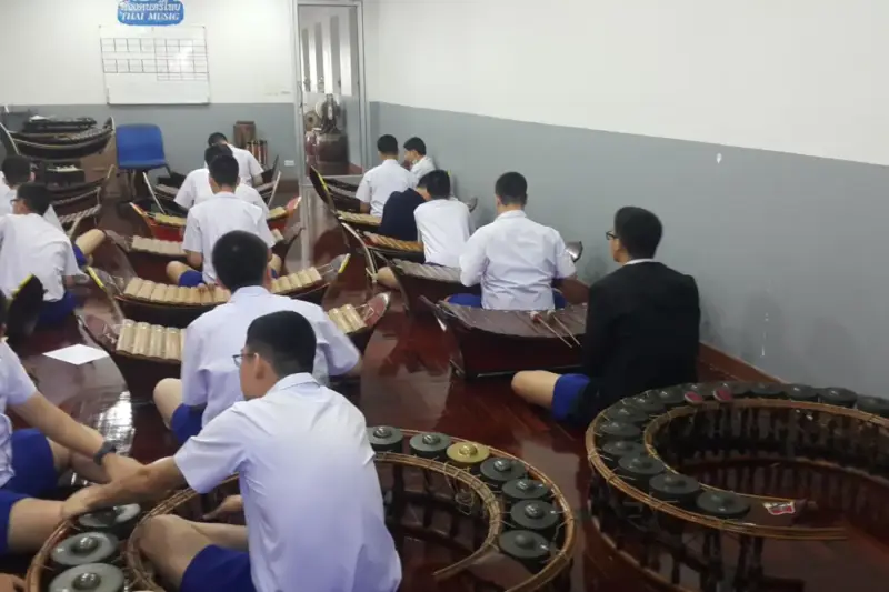 Grupo de estudiantes en un aula de música escolar practicando con instrumentos.