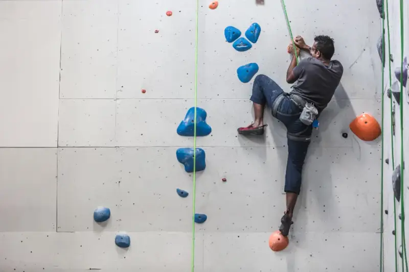 Escalador compitiendo en un rocódromo durante una prueba nacional de paraescalada.