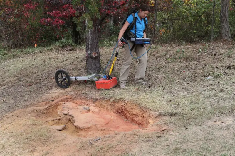 Plataforma de roca en un arroyo con huellas fosilizadas de dinosaurio, con especialistas trabajando al fondo