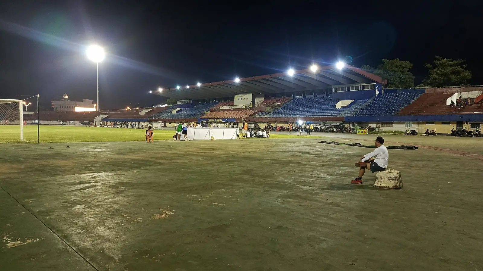 Estadio de fútbol de noche con el césped iluminado y una bandera de córner en primer plano
