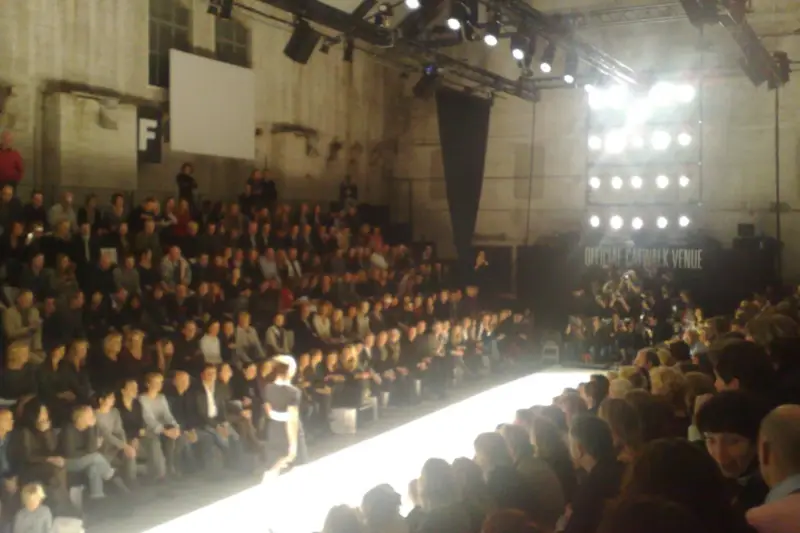 Pasarela iluminada de un desfile de moda con el público a los lados