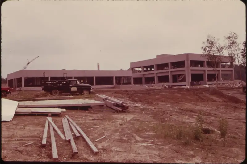 Obras de construcción de una planta potabilizadora junto al río, con tuberías, maquinaria y trabajadores en un entorno…