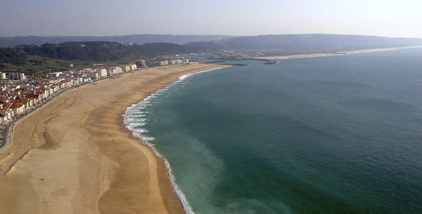 Varias personas formando una cadena en el mar para ayudar a alguien en una playa con oleaje