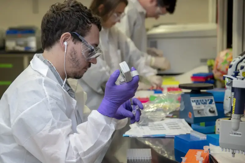 Investigadora ajustando un equipo de secuenciación de ADN en un laboratorio con luz natural