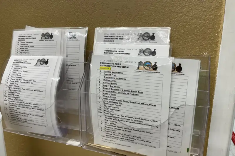 Interior de un garaje convertido en reparto de alimentos, con estanterías con comida y voluntarios atendiendo a personas de…
