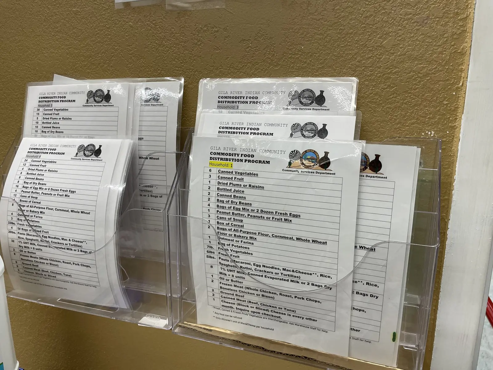 Interior de un garaje convertido en reparto de alimentos, con estanterías con comida y voluntarios atendiendo a personas de…