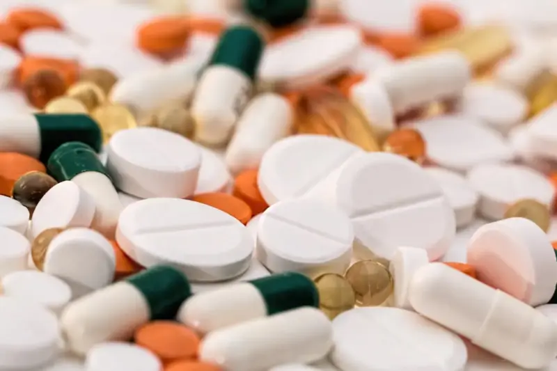 Farmacéutica entregando un envase de pastillas en el mostrador de una farmacia luminosa.