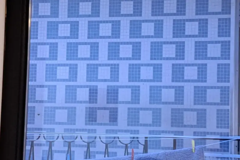 Estudiante limpiando con un pincel azulejos antiguos descubiertos bajo la cal en un muro de un convento.